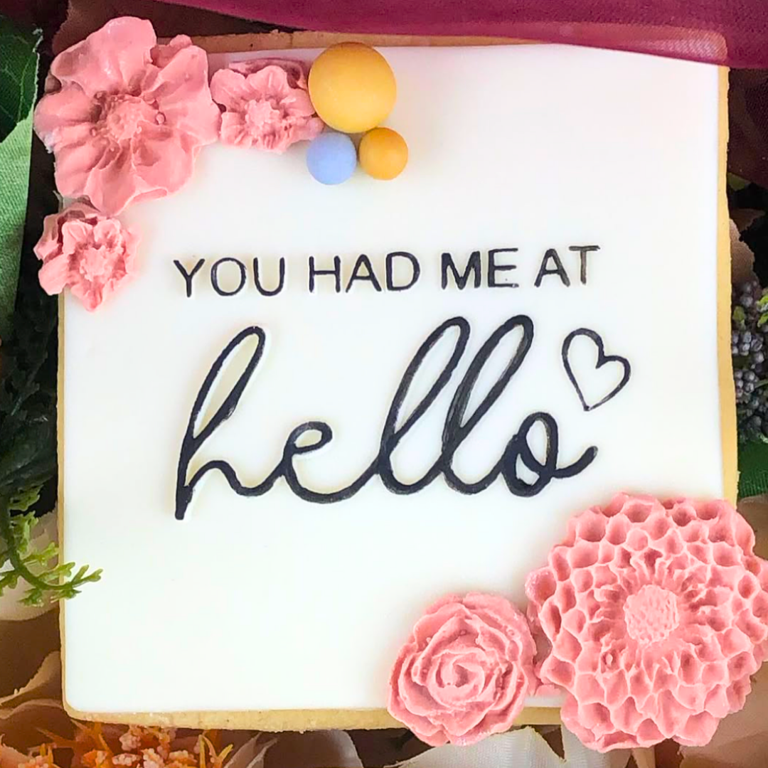 Decorative cookie with 'You had me at hello' text and pink flowers.
