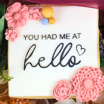 Decorative cookie with 'You had me at hello' text and pink flowers.