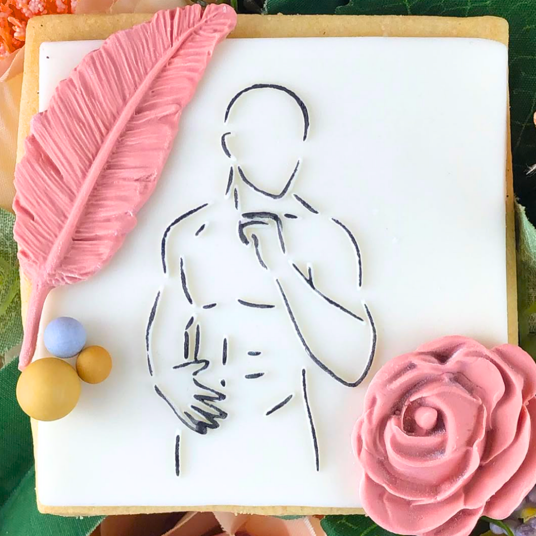 Decorative cookie with a pink feather, outline of a person, and pink rose on a white background.