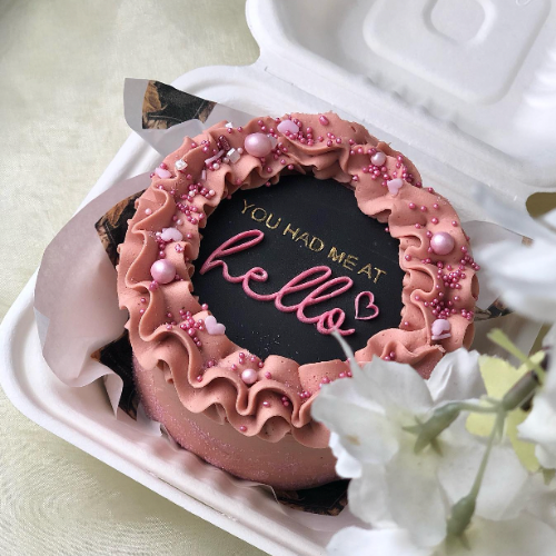 Pink decorated celebration cake with piped frosting and sprinkles
