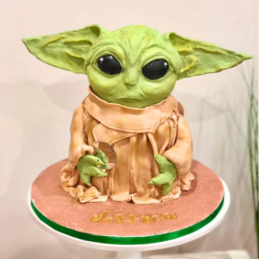 Green character figurine on a pink stand with a white background