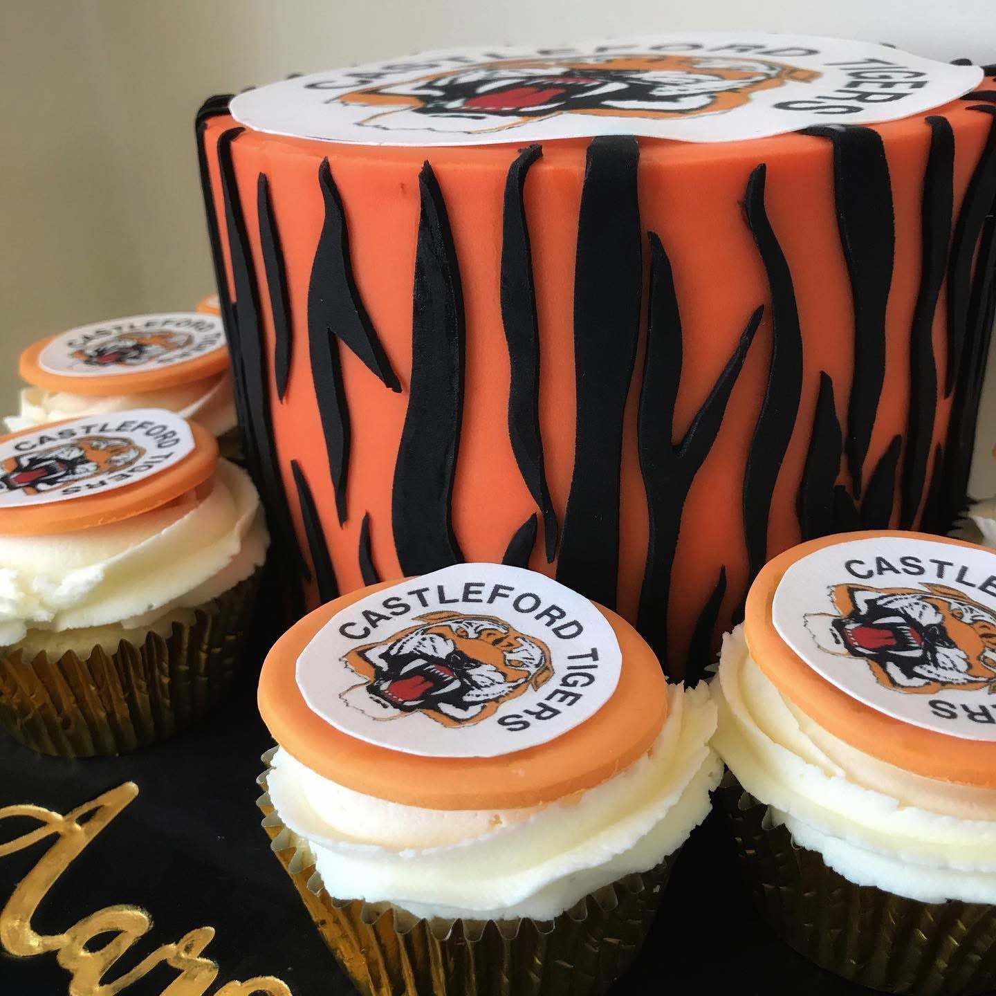 Cake and cupcakes with Castleford Tigers logo on a black surface