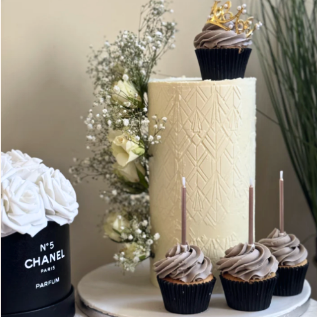 Decorative cake with cupcakes and a Chanel No. 5 bottle in the background
